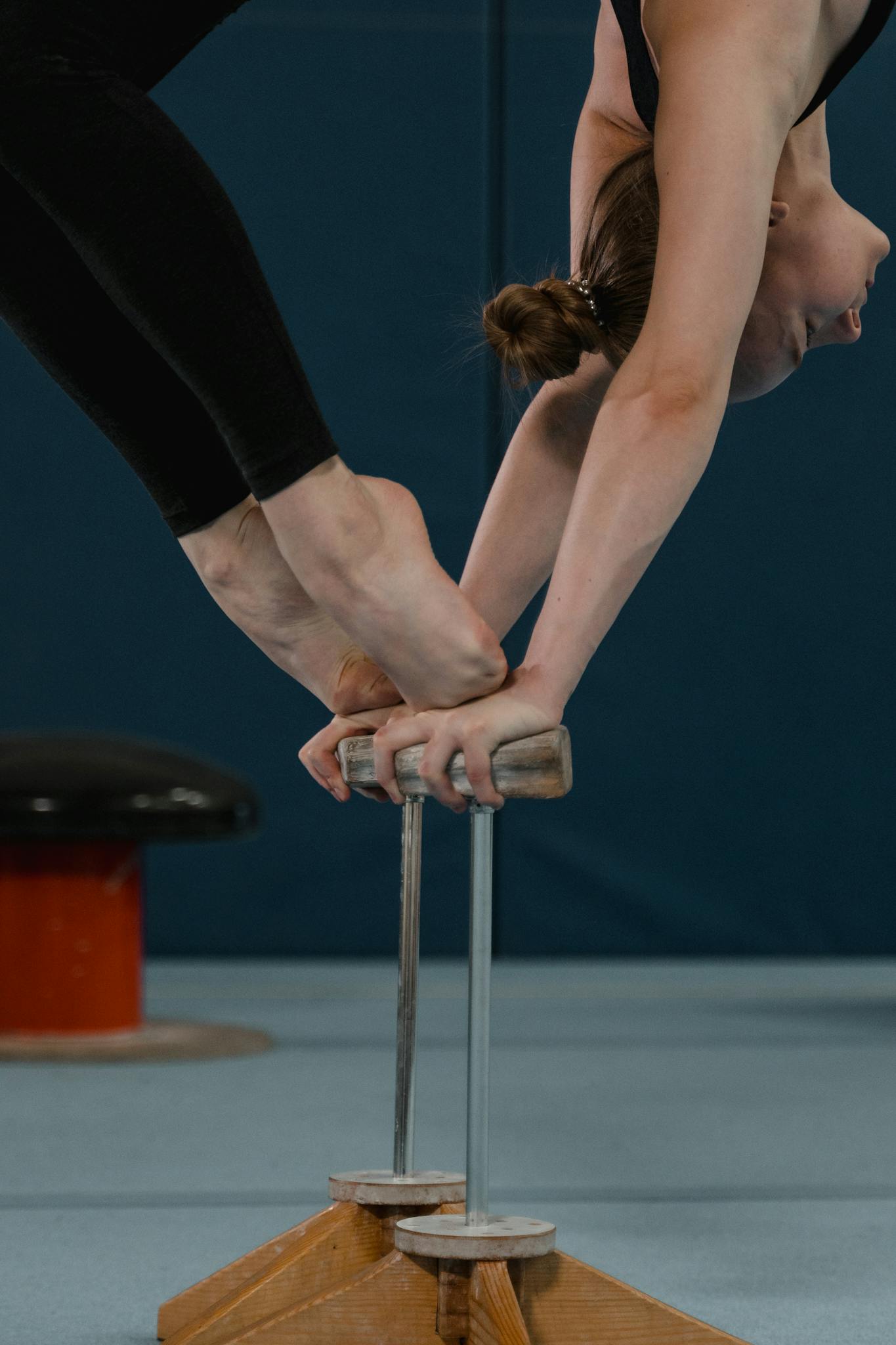 A gymnast gracefully balances in a handstand, showcasing strength and precision indoors.